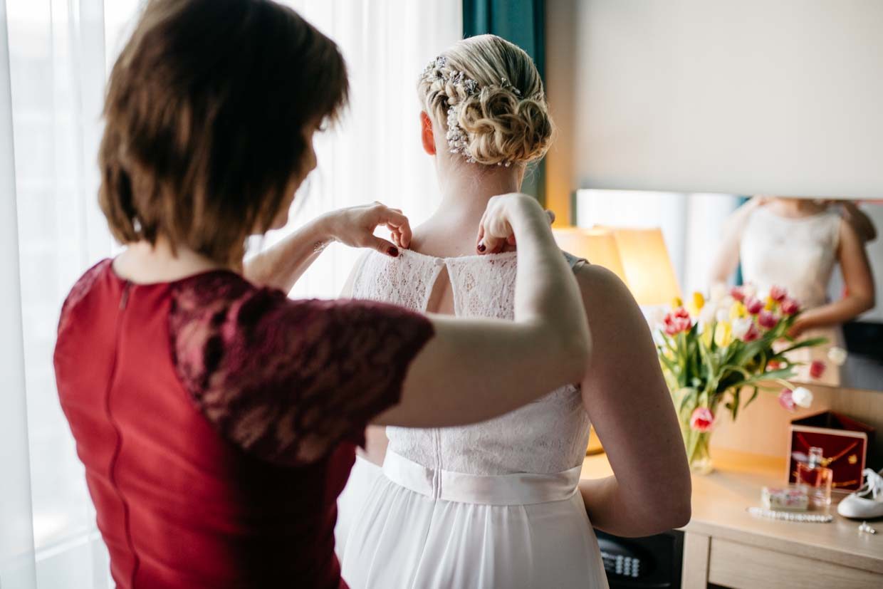 Trauzeugin hilft der Braut beim Anziehen